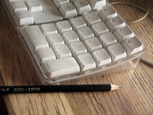 pencil next to a computer keyboard on desk