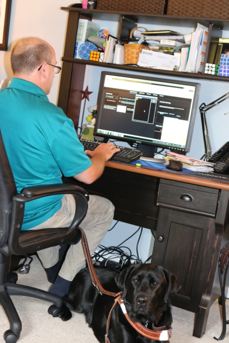 Dave working on computer with lead dog at his feet
