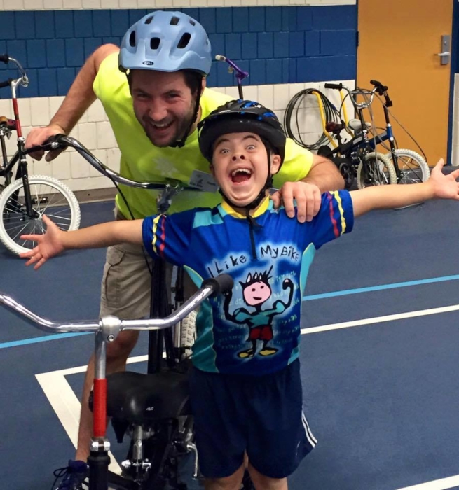 child with volunteer for i can bike program