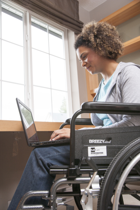 Woman using computer and sitting in a wheelchair