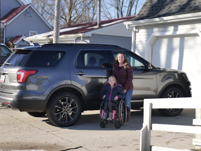 Sara beside her vehicle with her daughter