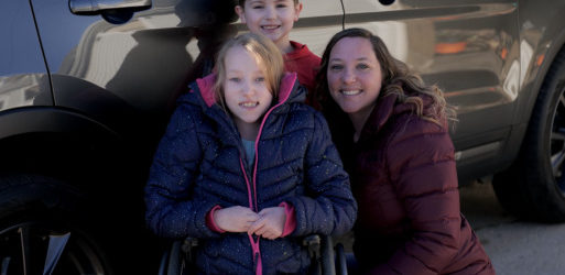 Sara beside her vehicle with her children