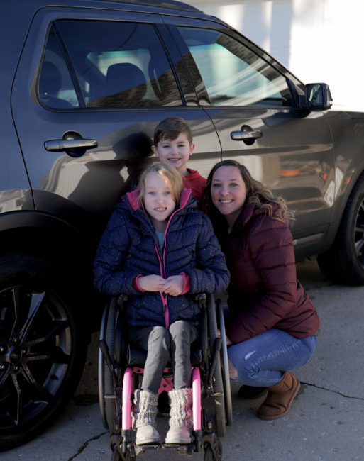 Sara beside her vehicle with her children