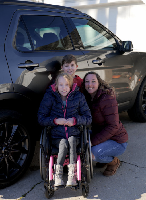 Sara beside her vehicle with her children