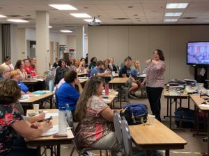 photo of a full day training. people sitting classroom style listening to presenter