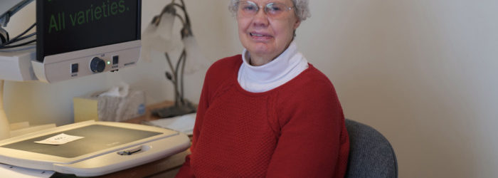 Photo of Candy Sherd sitting beside desktop magnifier