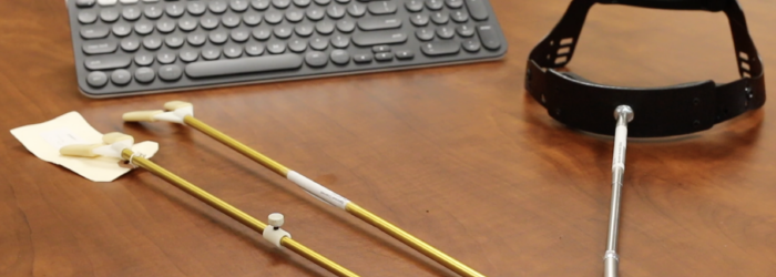 a keyboard, 2 mouth sticks and a head pointer sitting on a table
