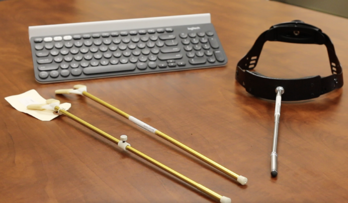 a keyboard, 2 mouth sticks and a head pointer sitting on a table